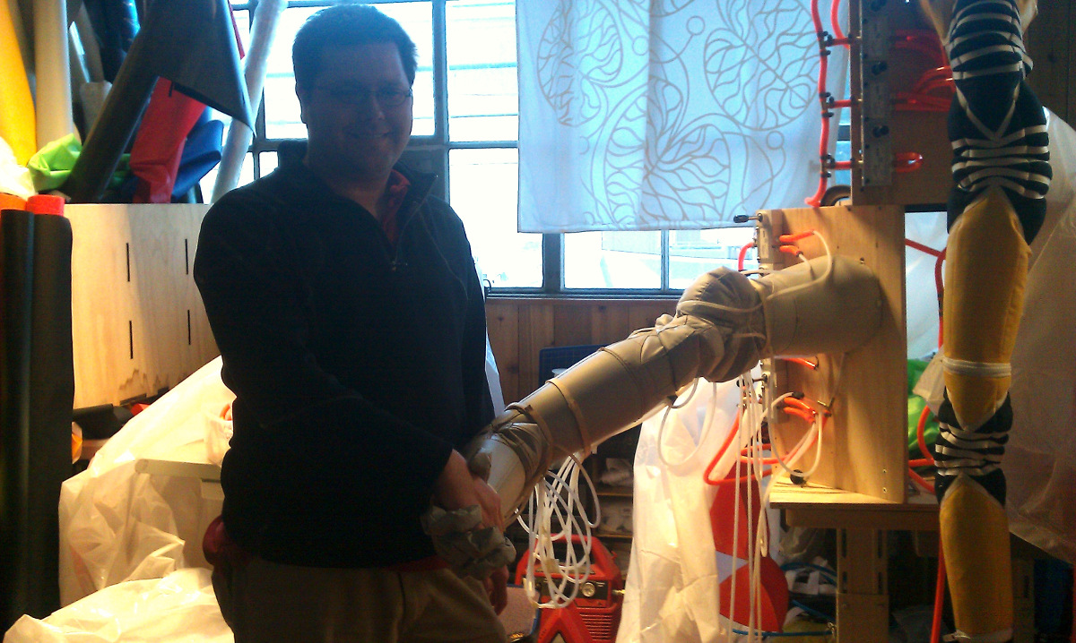 Travis Deyle shaking hands with an inflatable robot at Otherlab